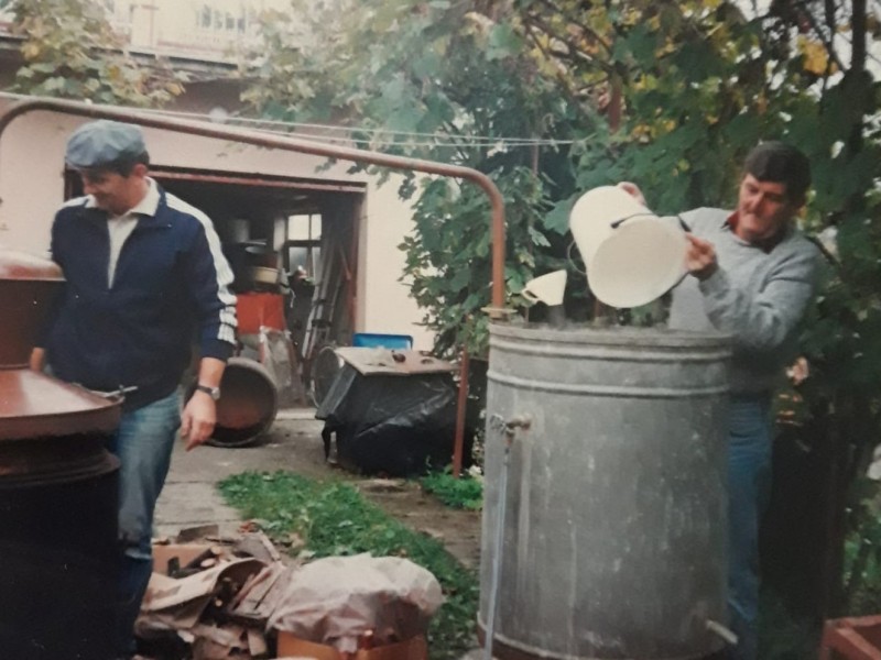 Pečenje rakije u dvorištu Mate i Ljerke Major u Pakracu. Pečenjari su Mato Major i Branko Marković. Rakija iz osamdesetih godina prošlog stoljeća pekla se od šljiva ubranih u Perđunovom voćnjaku iznad crkvice sv. Roka u Pakračkim vinogradima.